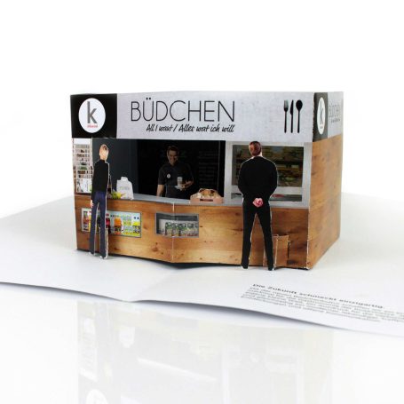 Pop up Szene eines Imbissstandes mit zwei Figuren, Menü und Holzdetails.